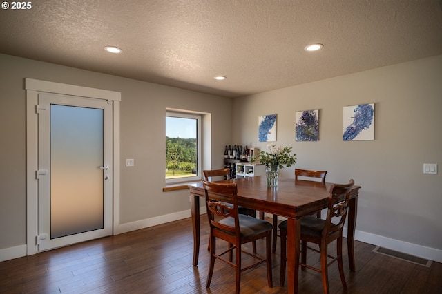 dining area with visible vents, a textured ceiling, baseboards, and dark wood-type flooring