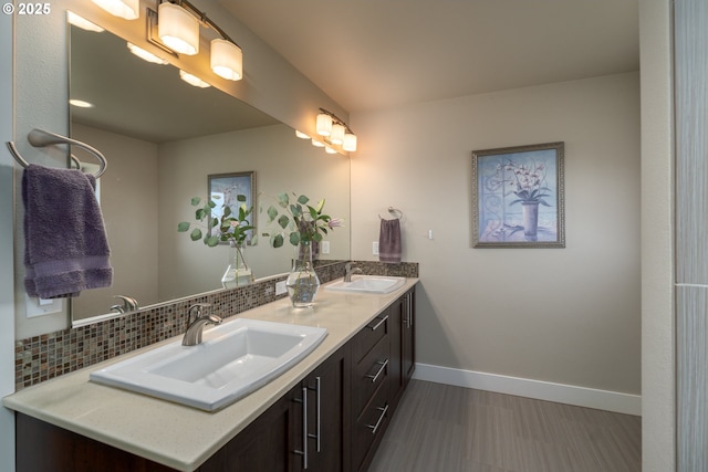 bathroom with baseboards, a sink, backsplash, and double vanity