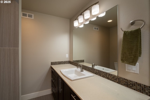 bathroom featuring toilet, baseboards, visible vents, and vanity