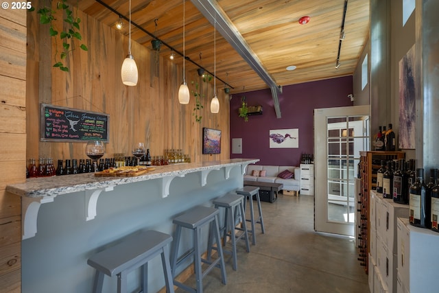 bar with a dry bar, finished concrete flooring, wood walls, and wood ceiling