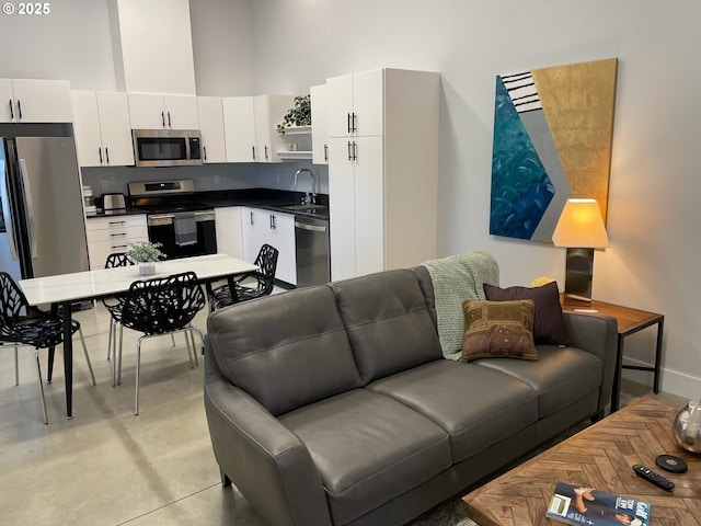 living area with finished concrete flooring, baseboards, and a towering ceiling