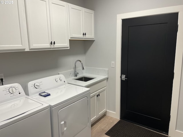 laundry room with light wood-type flooring, a sink, cabinet space, and washing machine and clothes dryer