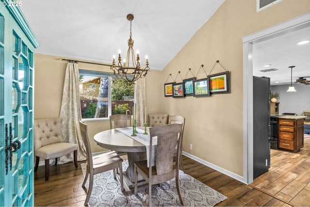 dining room with visible vents, hardwood / wood-style flooring, baseboards, lofted ceiling, and a notable chandelier