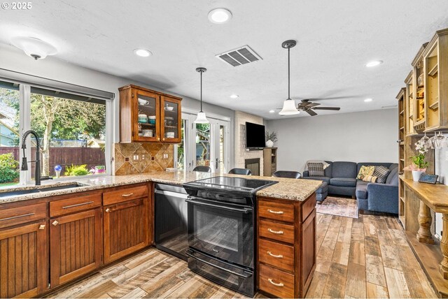 kitchen featuring a healthy amount of sunlight, electric range, a sink, visible vents, and a peninsula