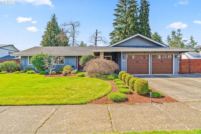 ranch-style home featuring a front lawn, fence, an attached garage, and concrete driveway