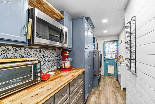 kitchen with a toaster, wooden counters, stainless steel microwave, tasteful backsplash, and light wood-style floors