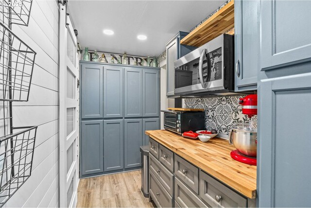 kitchen with backsplash, open shelves, butcher block counters, stainless steel microwave, and a toaster