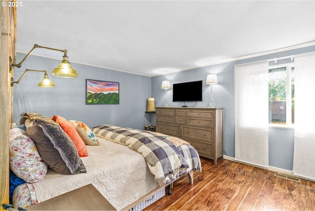 bedroom with wood finished floors, baseboards, and visible vents