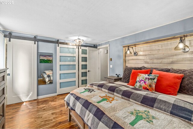 bedroom with a barn door and wood finished floors