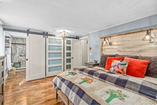 bedroom with a barn door and wood finished floors