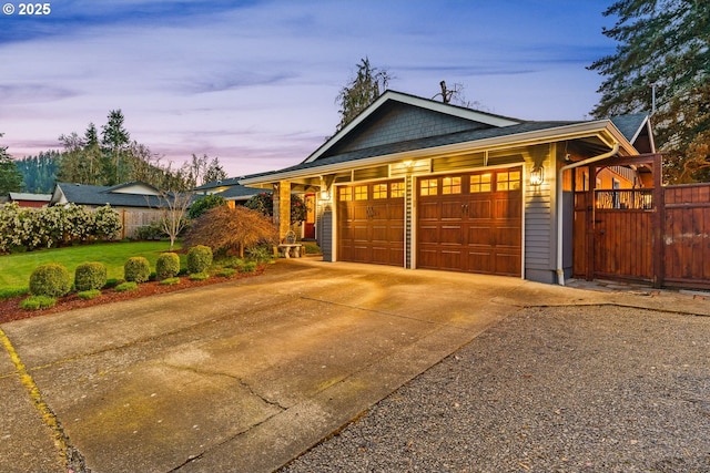 garage at dusk with a lawn, fence, and concrete driveway