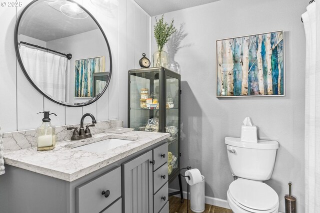 bathroom with baseboards, toilet, vanity, and wood finished floors