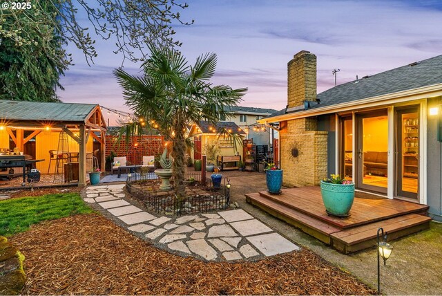 yard at dusk featuring a wooden deck and a patio area