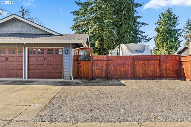 garage featuring concrete driveway and fence