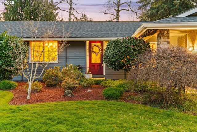 view of front of home with a front yard and a shingled roof