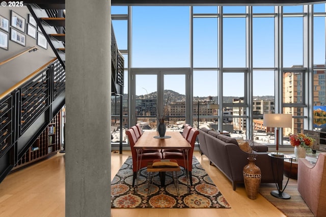 dining space with a high ceiling, a wall of windows, and wood finished floors