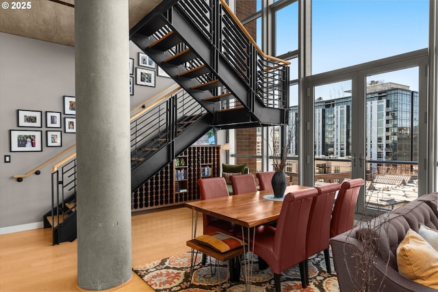 dining area with expansive windows, wood finished floors, stairs, and baseboards