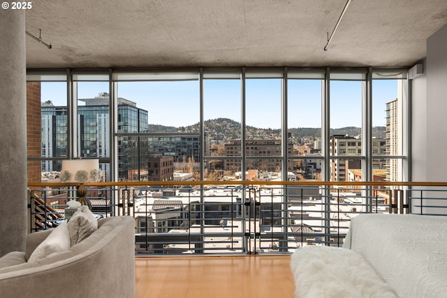 living area with a healthy amount of sunlight, a view of city, expansive windows, and wood finished floors