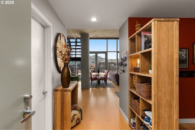 hall featuring baseboards, floor to ceiling windows, and wood finished floors