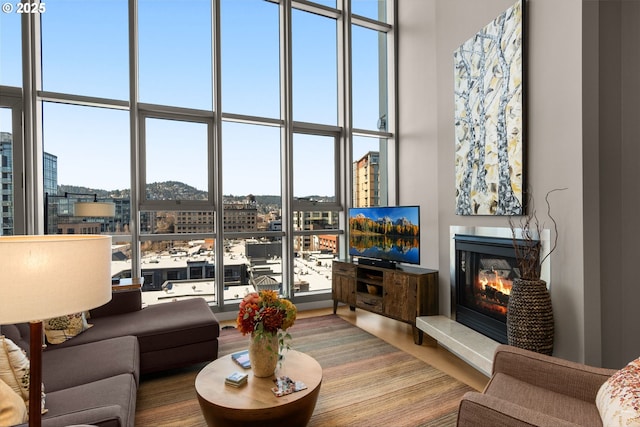 living area with a glass covered fireplace, floor to ceiling windows, and a towering ceiling