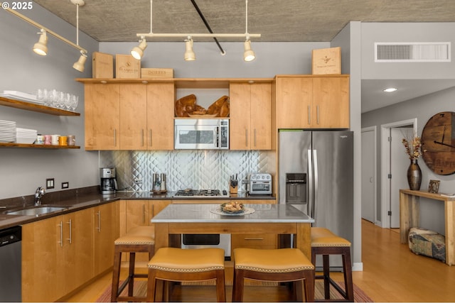 kitchen featuring open shelves, visible vents, appliances with stainless steel finishes, a sink, and a kitchen bar