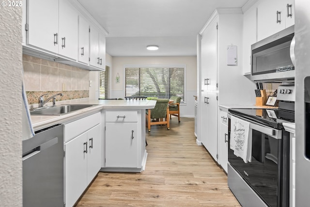 15565 SW 114th Ct Unit 23, Portland, OR 97224 - kitchen with stainless steel appliances, light wood-type flooring, light countertops, decorative backsplash, and white cabinetry