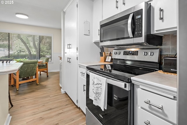 15565 SW 114th Ct Unit 23, Portland, OR 97224 - kitchen with appliances with stainless steel finishes, light wood-style floors, light countertops, white cabinets, and decorative backsplash