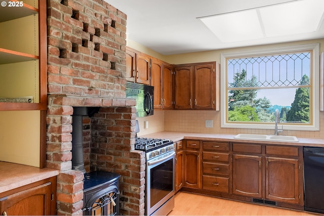 1005 Reserve St, Silverton, OR 97381 - kitchen featuring black appliances, a wood stove, light countertops, light wood-type flooring, and brown cabinets
