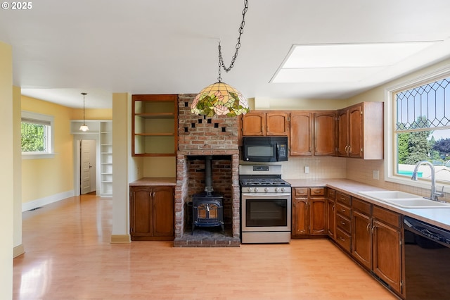 1005 Reserve St, Silverton, OR 97381 - kitchen featuring black appliances, a wood stove, light wood-style flooring, and backsplash