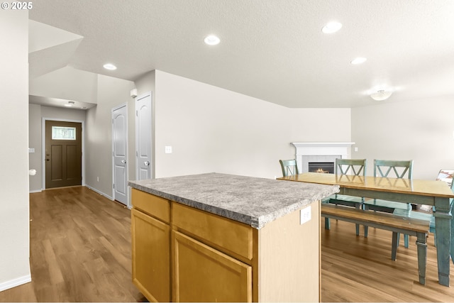 37125 Goldenrain St, Sandy, OR 97055 - kitchen with light wood-style flooring, a center island, a tiled fireplace, a textured ceiling, and recessed lighting