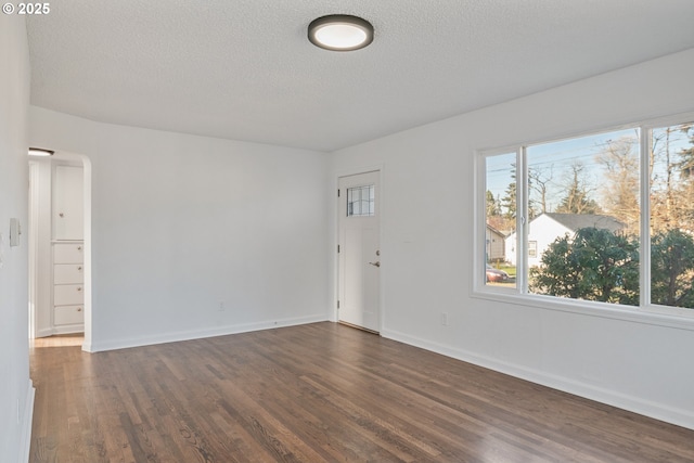 unfurnished room featuring dark wood-type flooring and a textured ceiling