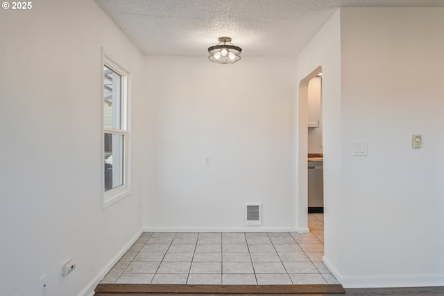 unfurnished room featuring a textured ceiling and light tile patterned floors