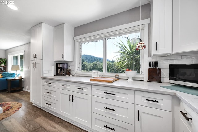 48521 E 1st St, Oakridge, OR 97463 - kitchen featuring stainless steel microwave, decorative backsplash, dark wood-style flooring, and white cabinets