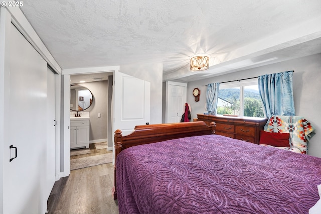 48521 E 1st St, Oakridge, OR 97463 - bedroom featuring wood finished floors, a textured ceiling, a sink, and baseboards