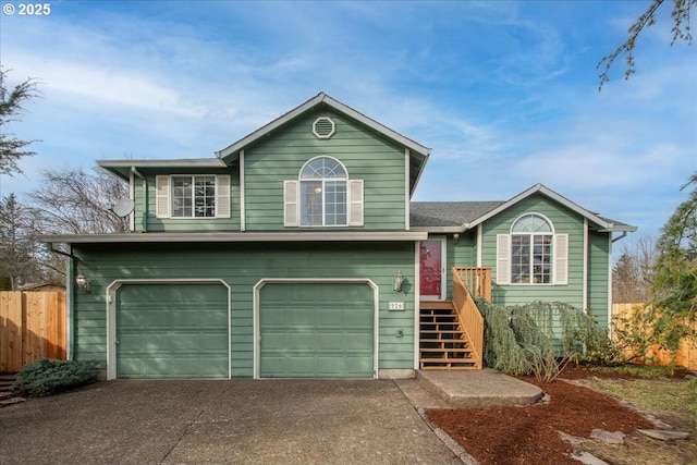 split level home with a garage, concrete driveway, and fence