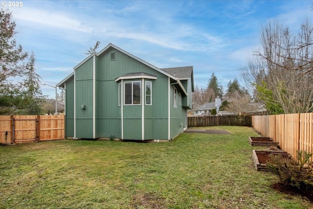 back of house featuring a fenced backyard, a vegetable garden, and a lawn