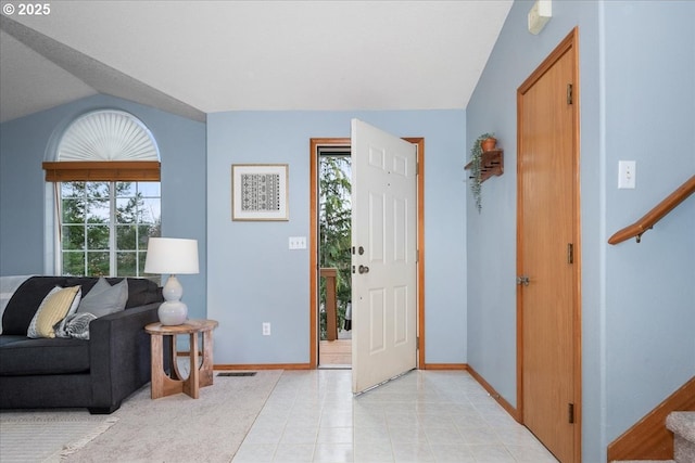 entrance foyer featuring vaulted ceiling, stairway, baseboards, and light tile patterned floors