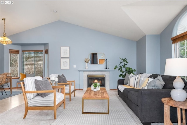 living room featuring lofted ceiling, a fireplace, and baseboards