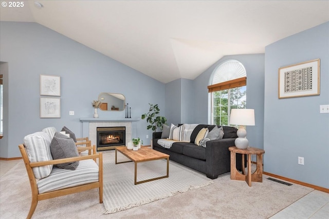 living area featuring lofted ceiling, visible vents, baseboards, and a tile fireplace