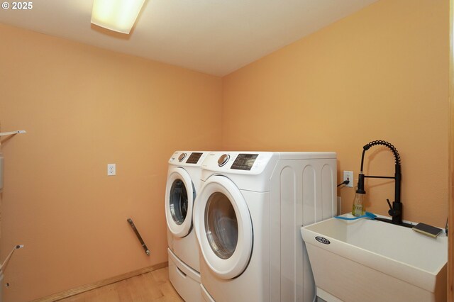 laundry area with washing machine and clothes dryer and light wood finished floors