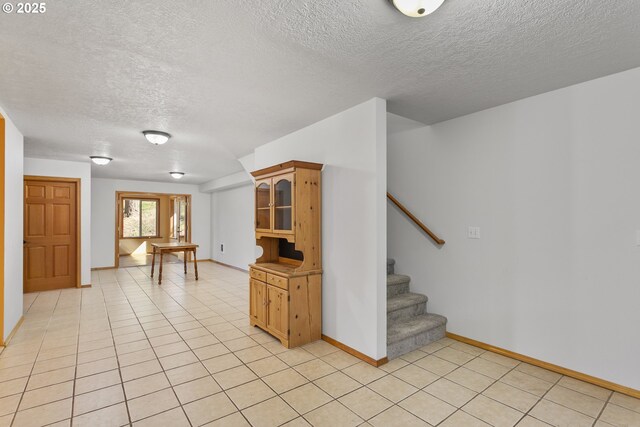interior space featuring a textured ceiling, baseboards, and light tile patterned floors