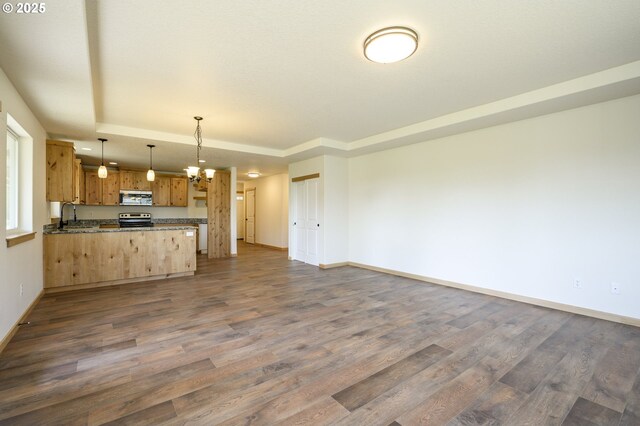 440 NW Gutbrod St, Sheridan, OR 97378 - unfurnished living room featuring dark wood-type flooring, a sink, baseboards, and a tray ceiling