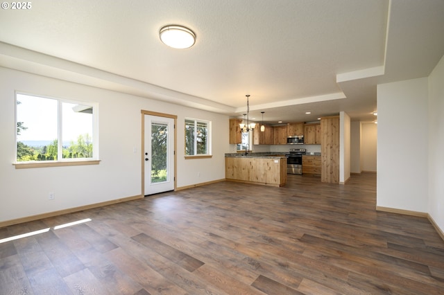 440 NW Gutbrod St, Sheridan, OR 97378 - unfurnished living room featuring baseboards, a raised ceiling, a notable chandelier, and dark wood-style floors