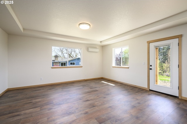 440 NW Gutbrod St, Sheridan, OR 97378 - spare room featuring a textured ceiling, a raised ceiling, baseboards, an AC wall unit, and wood finished floors