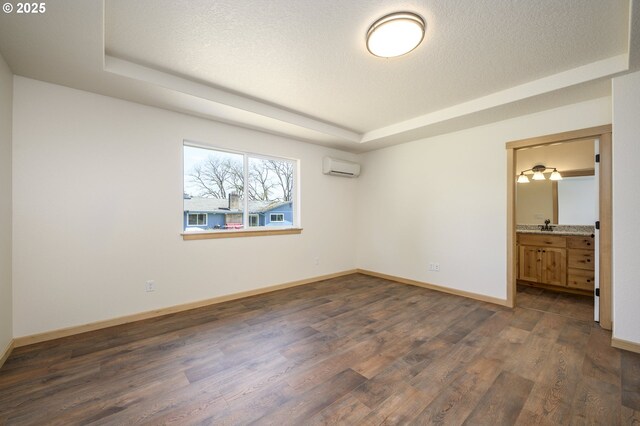440 NW Gutbrod St, Sheridan, OR 97378 - unfurnished bedroom with ensuite bath, a wall mounted air conditioner, dark wood-style flooring, baseboards, and a raised ceiling