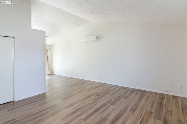517 Anthony Dr, Boardman, OR 97818 - unfurnished room featuring a textured ceiling, wood finished floors, vaulted ceiling, a wall mounted AC, and baseboards