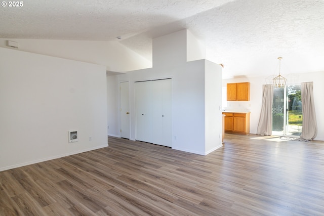 517 Anthony Dr, Boardman, OR 97818 - unfurnished living room featuring a chandelier, a textured ceiling, wood finished floors, vaulted ceiling, and baseboards