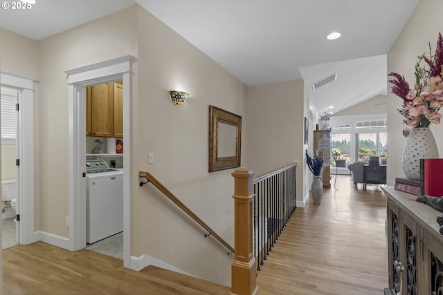 corridor featuring lofted ceiling, washer / clothes dryer, and light hardwood / wood-style floors