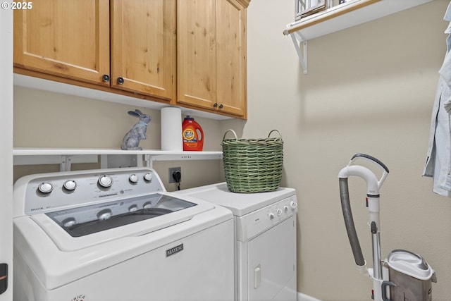 laundry room featuring separate washer and dryer and cabinets