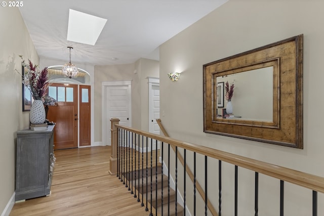 hall featuring a skylight, a chandelier, and light hardwood / wood-style flooring